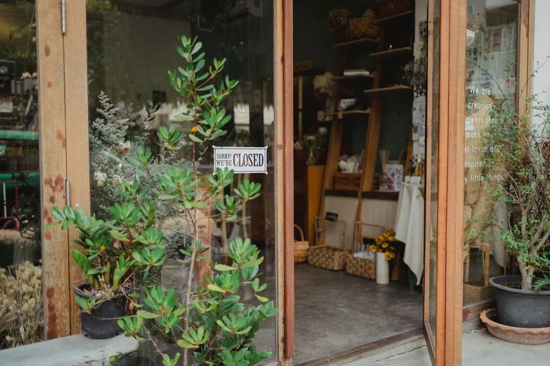 A 'Sorry, we're closed' sign hanging in the glass door of a small plant shop