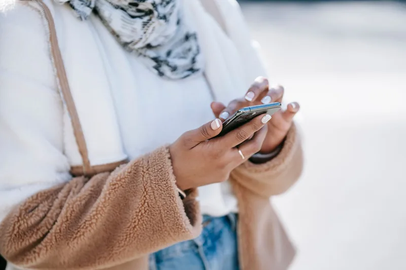 Person scrolling through their phone outdoors, where most small-business ads are seen