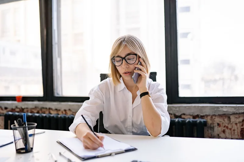 Business owner on a phone call taking notes at a desk