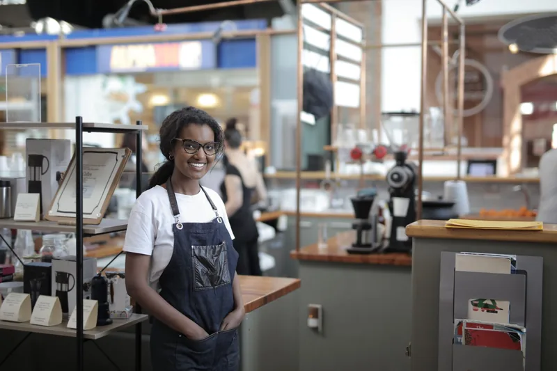 Smiling small shop owner in an apron standing in her store