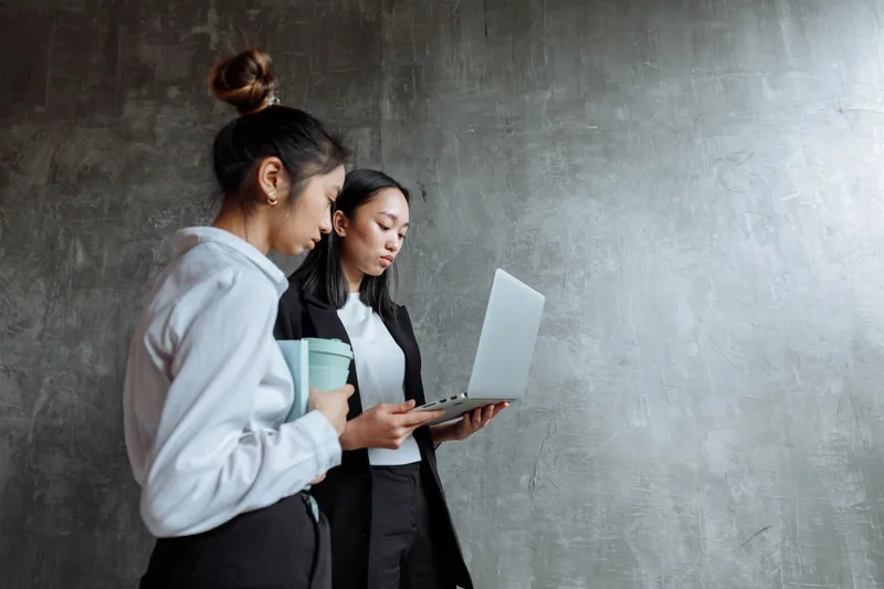 Two coworkers reviewing information together on a laptop in an office