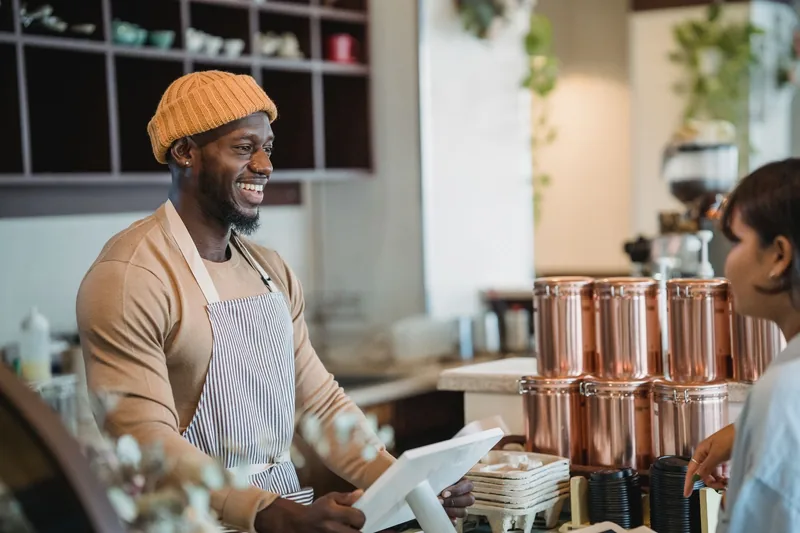 Small-business owner talking with a customer at the counter of a cafe