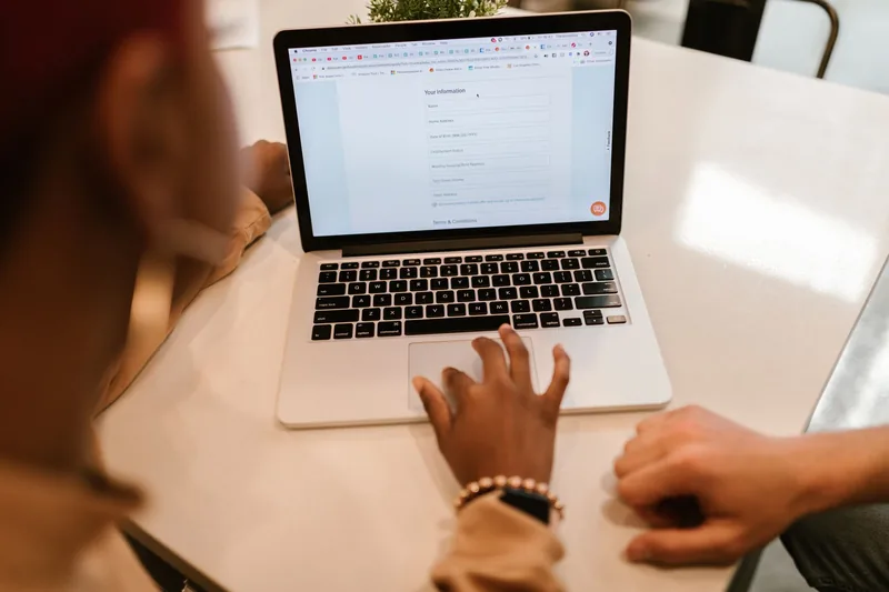 Person filling out an online contact form on a laptop at a white table