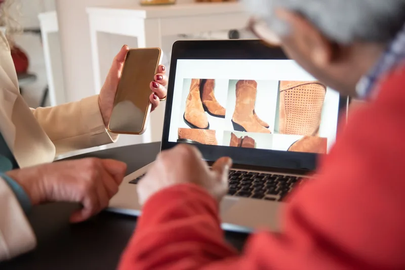Two people looking at an online store product grid on a laptop screen