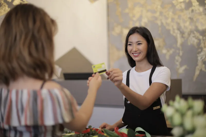 Shop employee handing a card back to a customer at a retail counter
