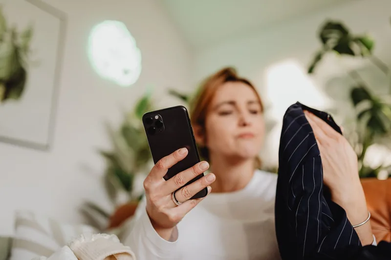 Woman comparing a clothing item against a product page on her smartphone