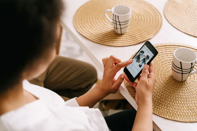 Woman scrolling a search result on her smartphone at a kitchen table