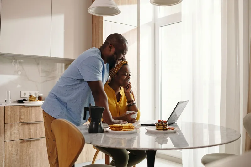 Couple looking at a laptop together at their kitchen table