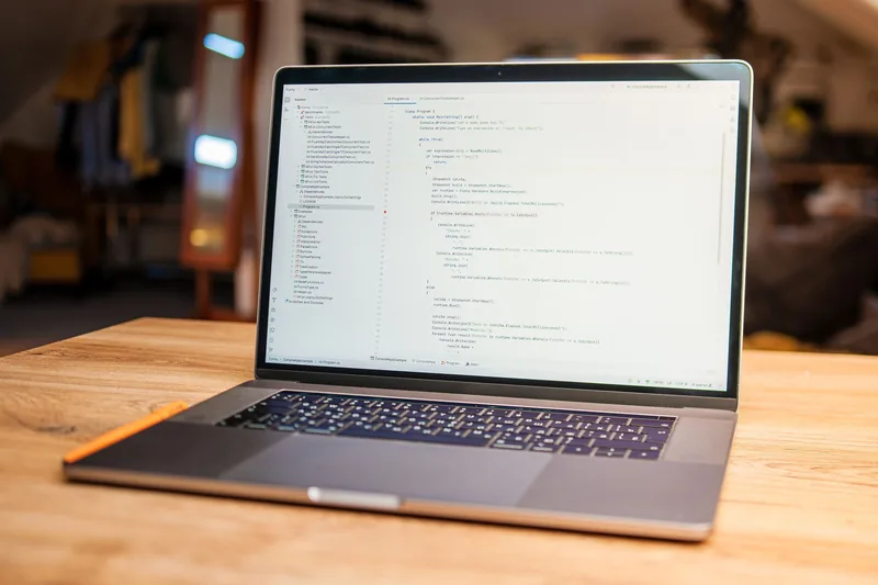 Laptop on a wooden desk showing website code in an editor