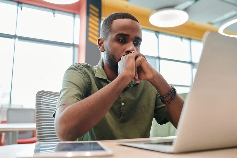 Business owner studying results on a laptop screen with his hand at his chin