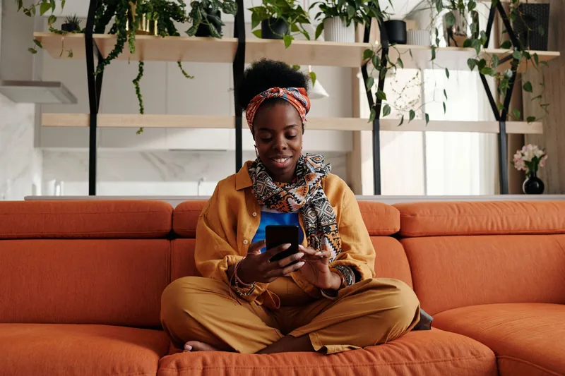 Woman sitting on a couch scrolling social media on her phone
