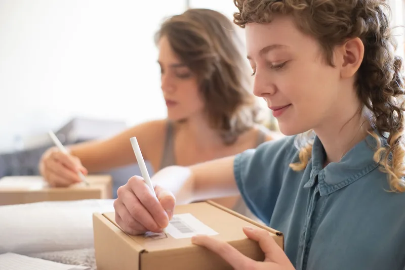 Two small-business owners labelling shipping boxes for online orders