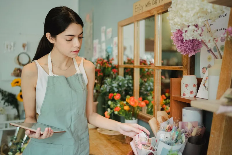 Small business owner reviewing orders on a tablet in her flower shop
