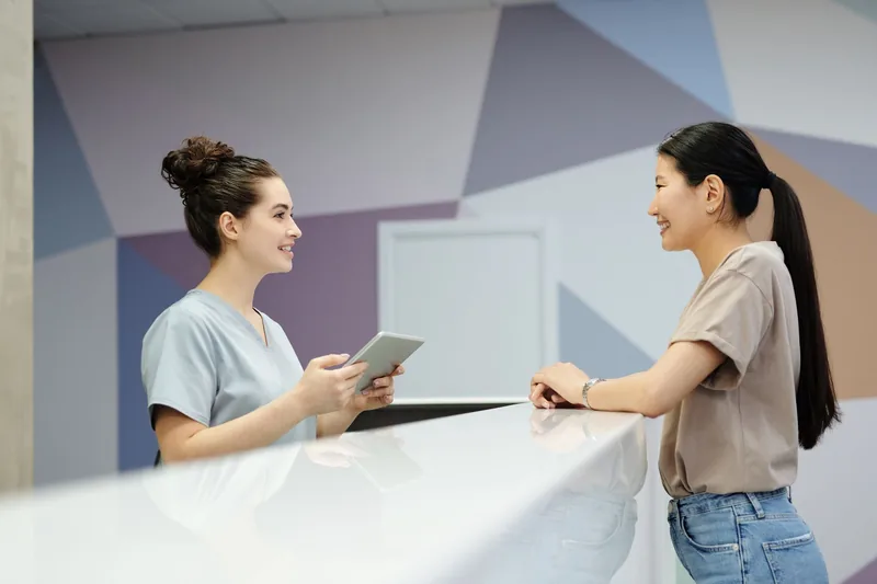 Receptionist with a tablet greeting a client at the front desk