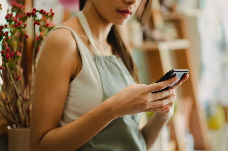 Shop owner in an apron checking a new lead notification on her phone